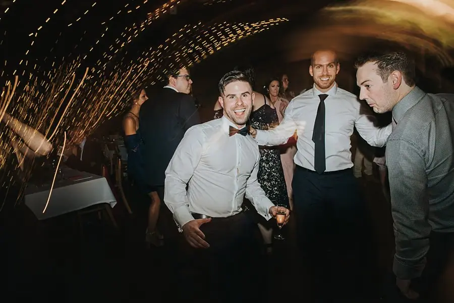 Men dancing and making playful poses beneath golden light streaks.