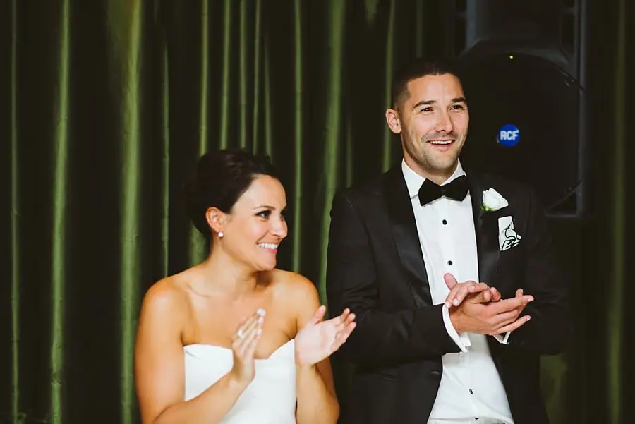 Bride and groom smiling and applauding during the reception