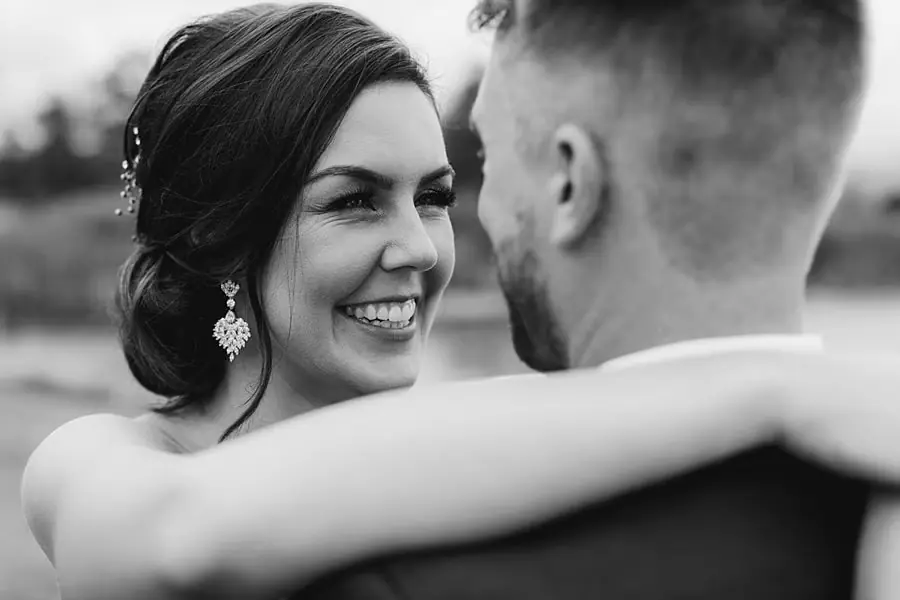 Black and white portrait of the bride smiling while holding the groom.