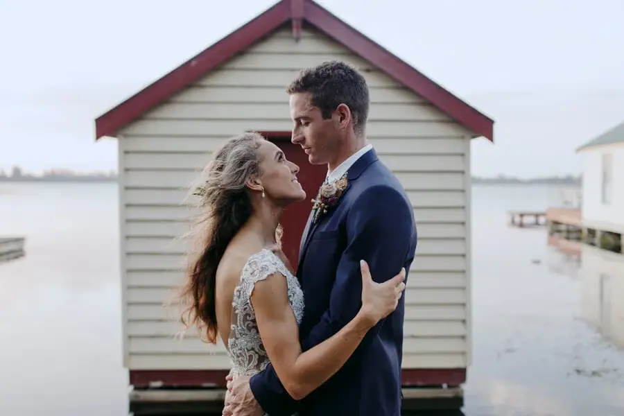 Couple embracing beside a small seaside shed.