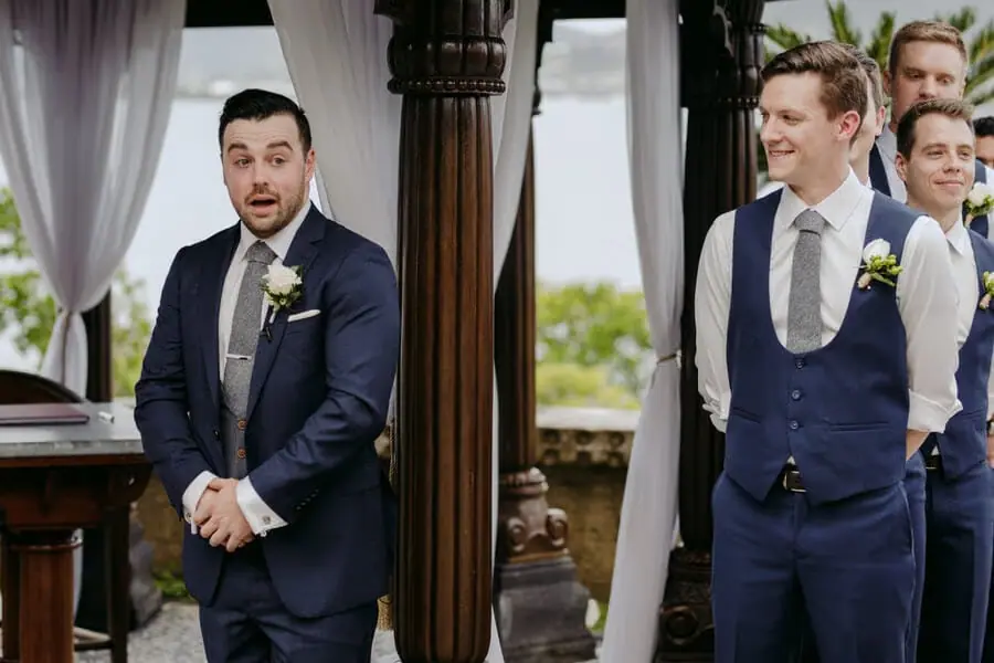 Groom and companions reacting with smiles beside the ceremony doorway.