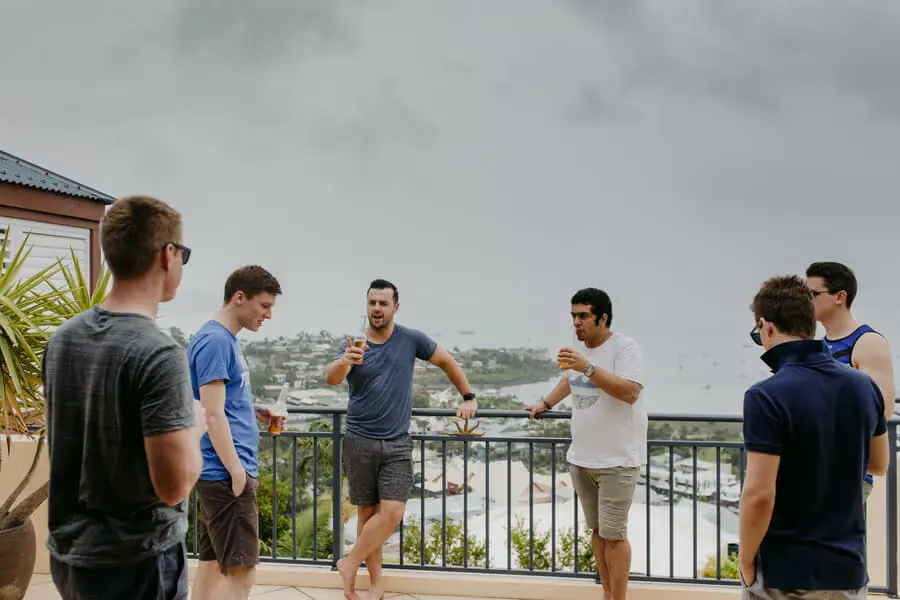 Men chatting on a terrace beneath a grey sky.
