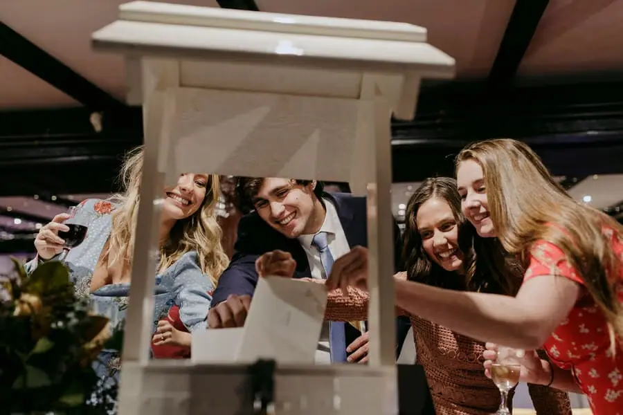 Guests laughing and posing through a decorative wooden frame.
