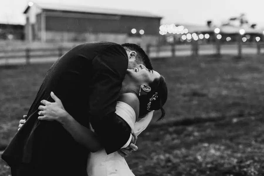 Black-and-white photograph of a groom dipping and kissing the bride outdoors.