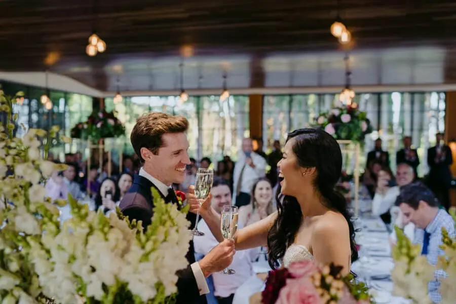 Bride and groom raising glasses together at the reception.