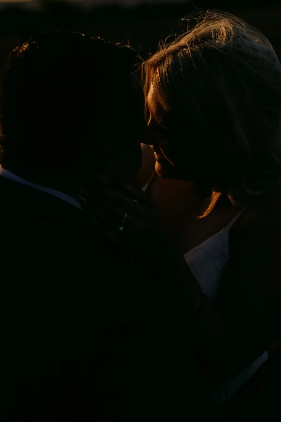 Close portrait of a suited man in dim golden light.