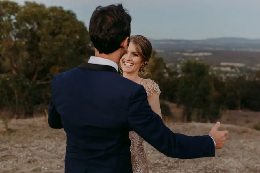 Couple embracing on a hillside overlooking distant countryside.