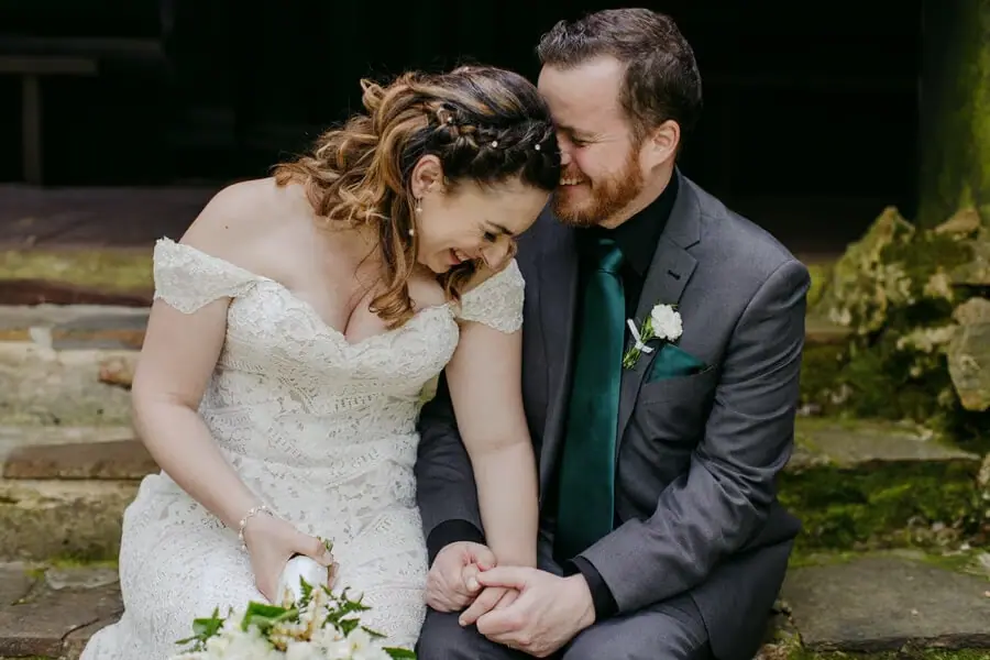 Bride and groom sitting close together on stone steps.
