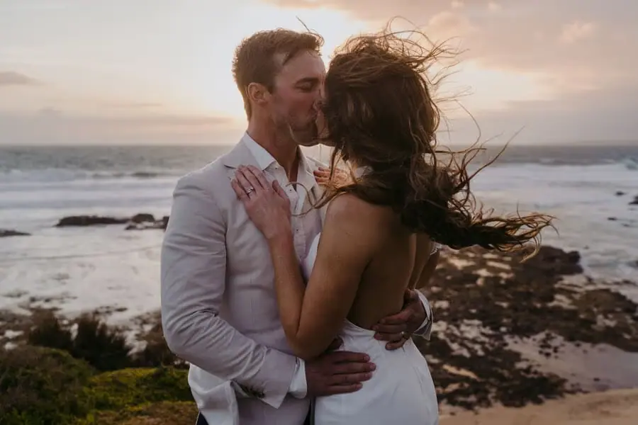 Couple embracing beside the sea in warm sunset light.