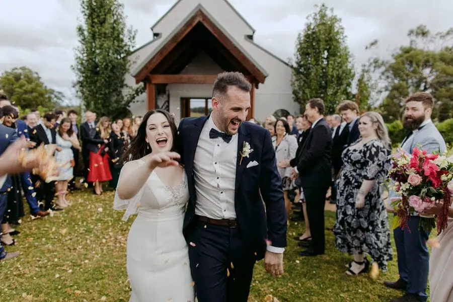 Couple laughing while leaving a chapel through their guests.