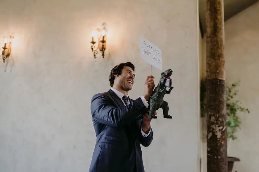 Man holding a small figure and sign while smiling inside a chapel.