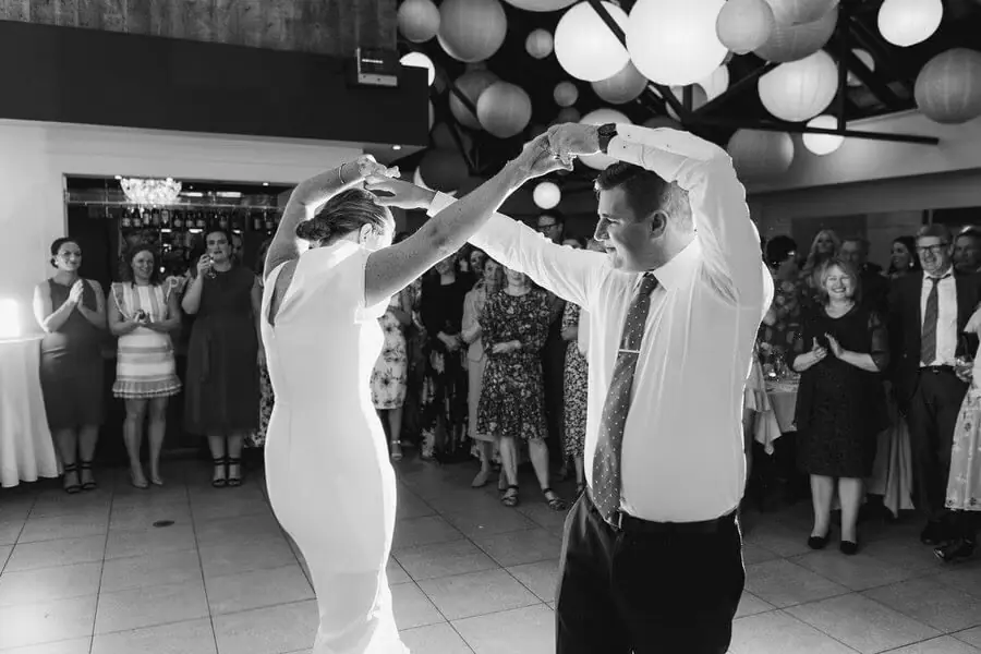Black-and-white photograph of a couple turning together on the dance floor.