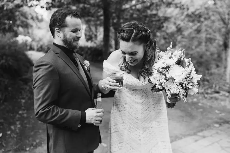 Black-and-white photograph of a bride looking down beside the groom and her bouquet.