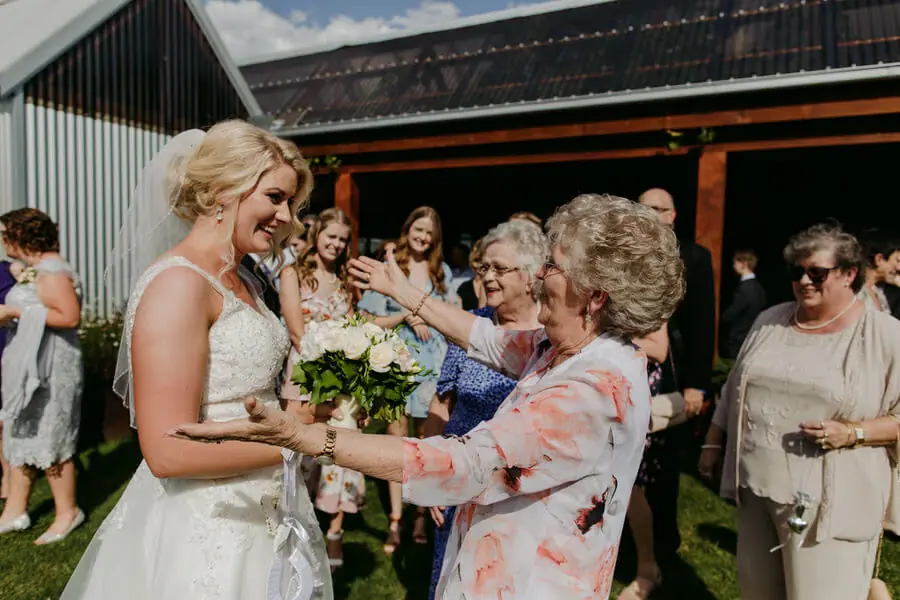 Bride greeting an older woman outside the reception building.