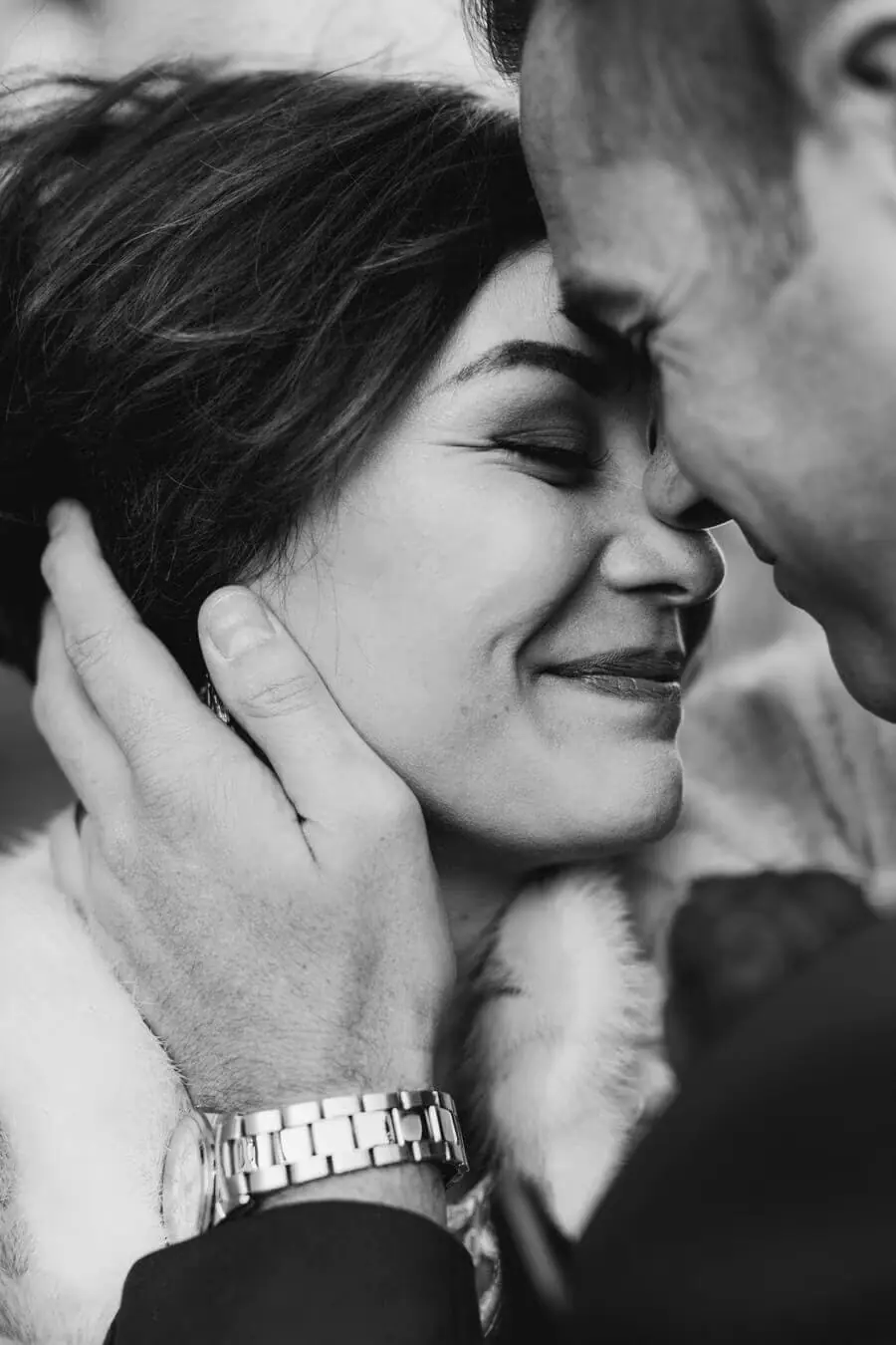 Black-and-white close-up of a man kissing a smiling woman's forehead.
