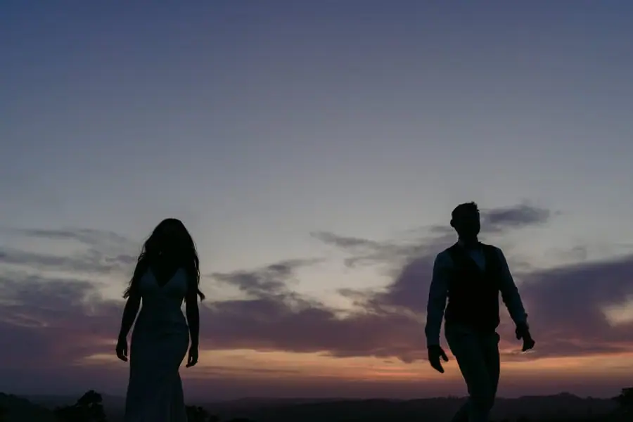 Two figures silhouetted against a colourful dusk sky.