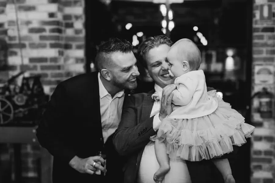 Black-and-white photograph of a couple smiling at a baby held between them.