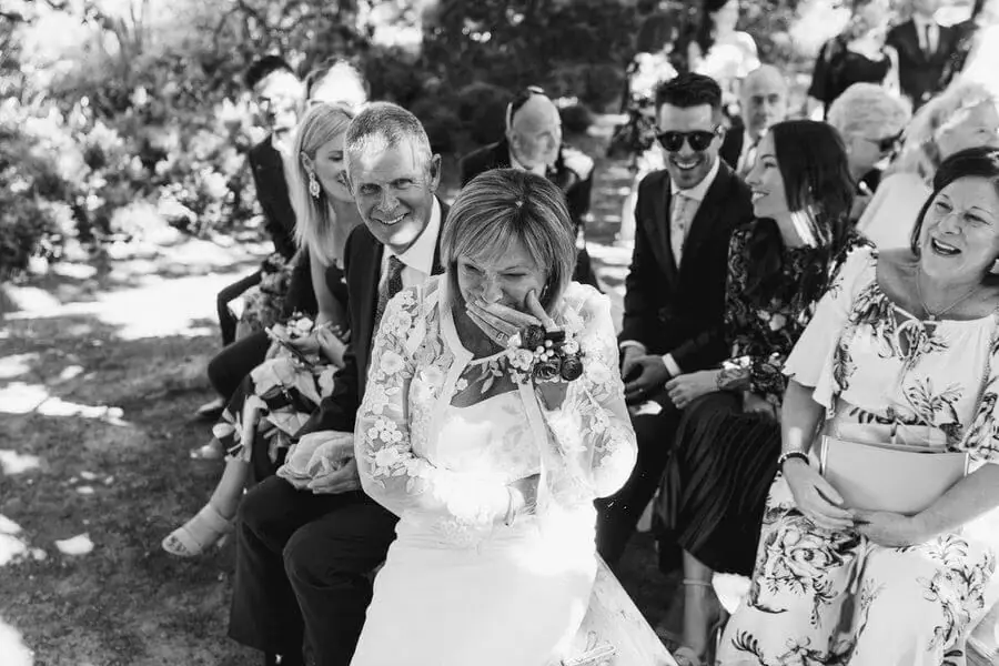 Black-and-white photograph of seated guests, including a woman wiping her eyes.