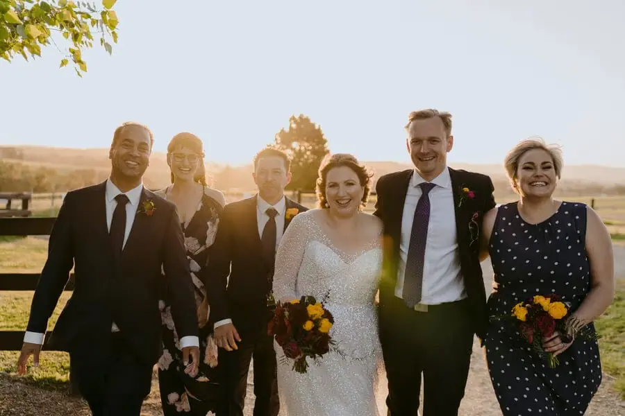 Bride and guests standing together in warm sunset light.
