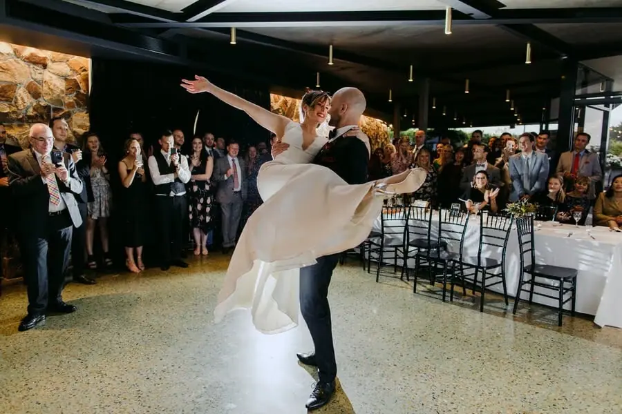 Groom lifting the bride across his arms on the dance floor.