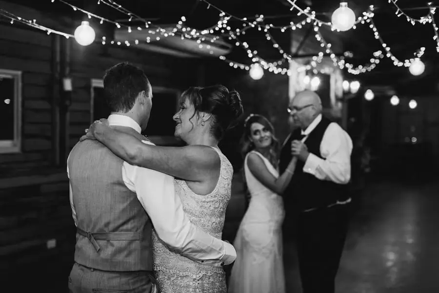 Black-and-white photograph of couples dancing beneath string lights.