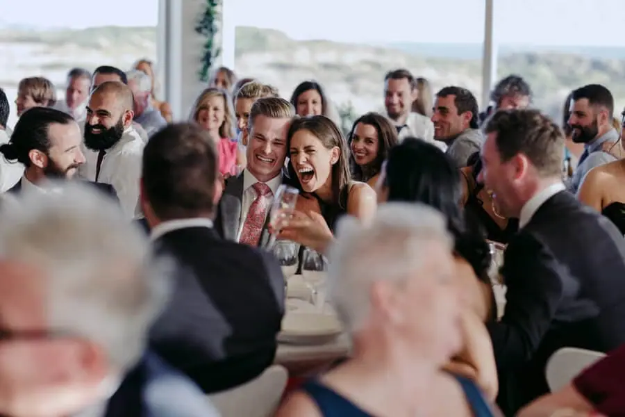 Guests laughing around an outdoor reception table.