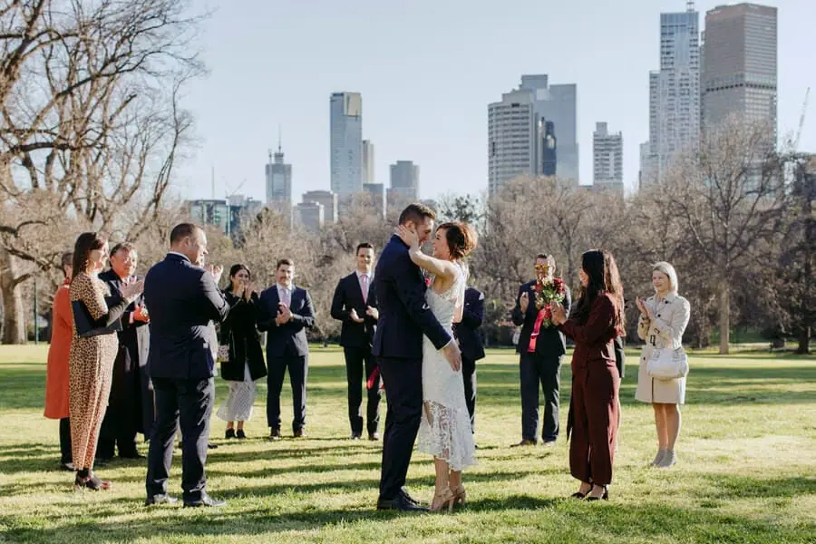 Guests gathered at a park ceremony with a city skyline beyond.