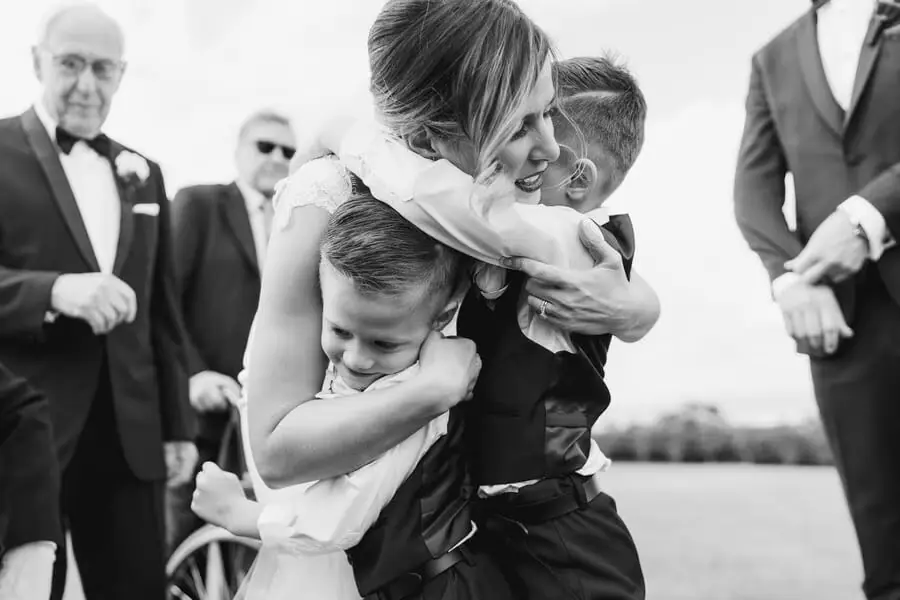Black-and-white photograph of a man embracing two children outside.