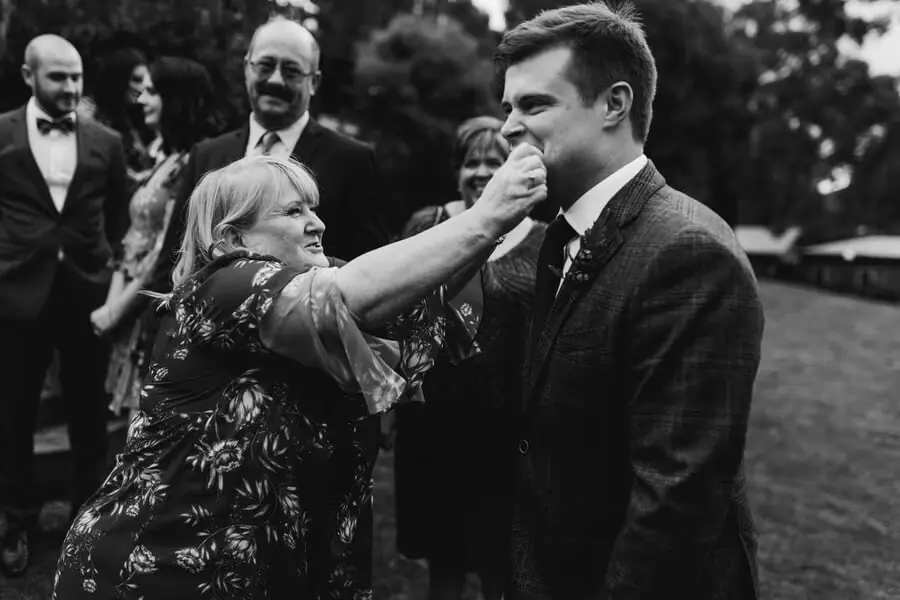 Black-and-white photograph of a woman touching a smiling groom's cheek.
