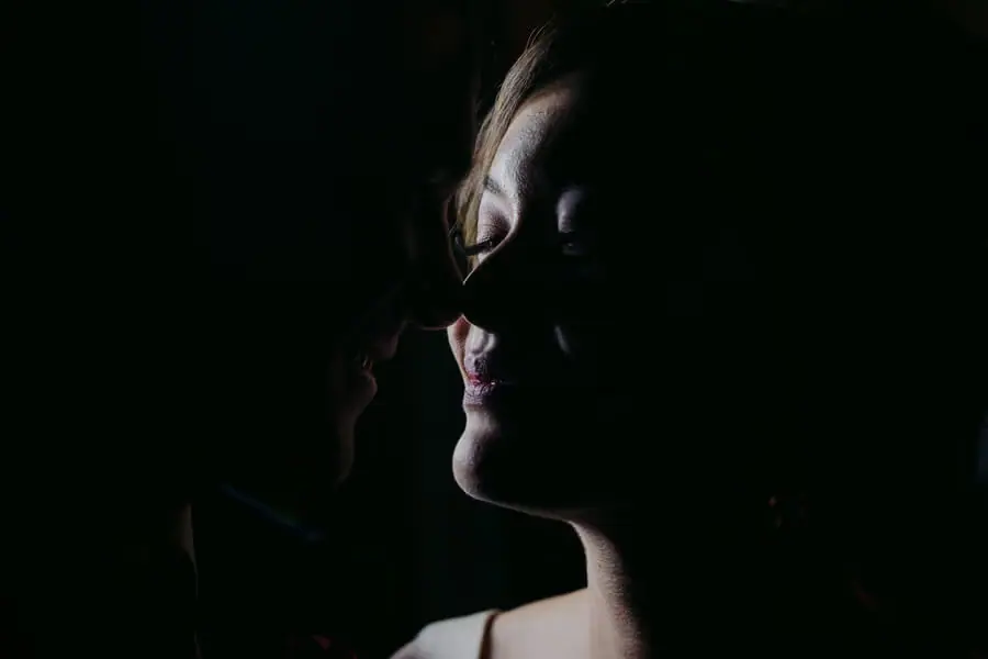 Close portrait of the bride's softly lit smiling face against a dark background.
