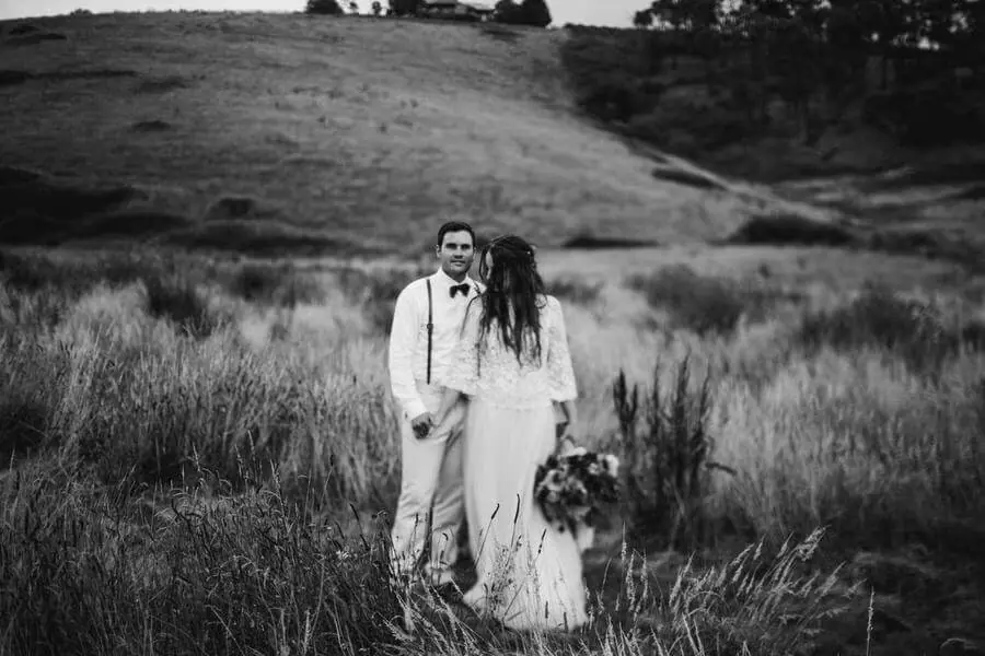 Black-and-white portrait of a couple standing together in a grassy field.