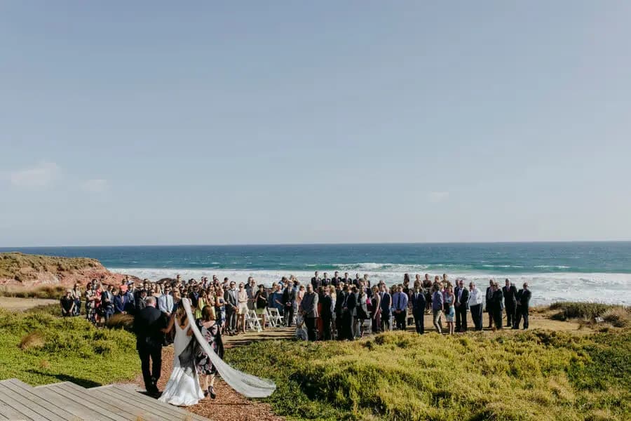 Wide view of guests gathered at a seaside wedding ceremony.