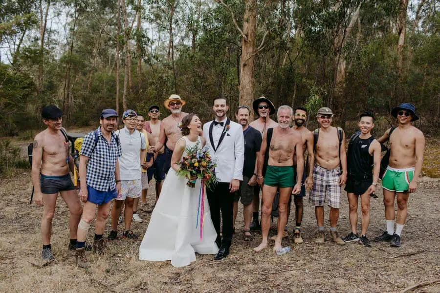 Bride and groom posing with a group of casually dressed men in woodland.