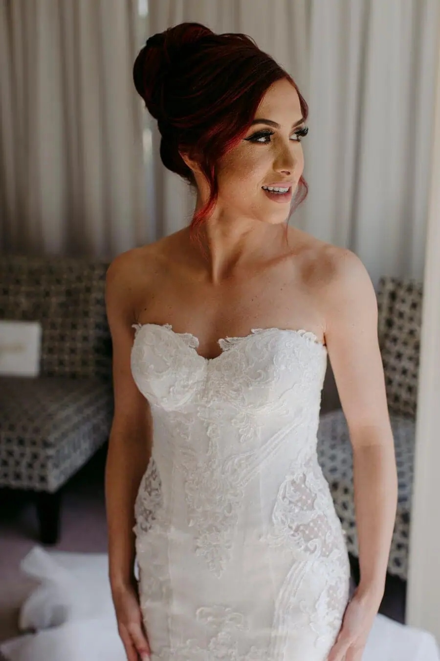 Bride standing beside a window in a strapless wedding dress.