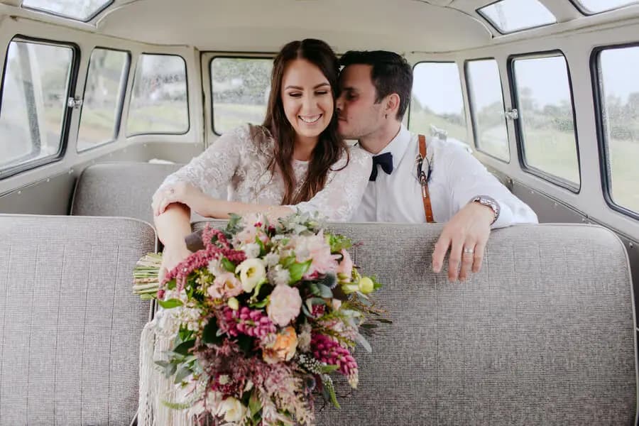 Couple sitting together inside a vintage van with a colourful bouquet.