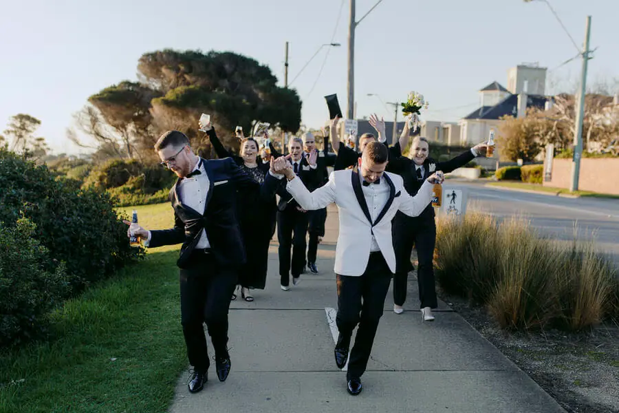 Men in dinner jackets walking playfully along a footpath.