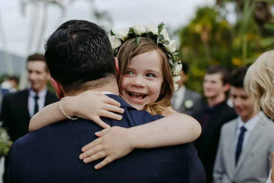 Young girl hugging a man and smiling over his shoulder.