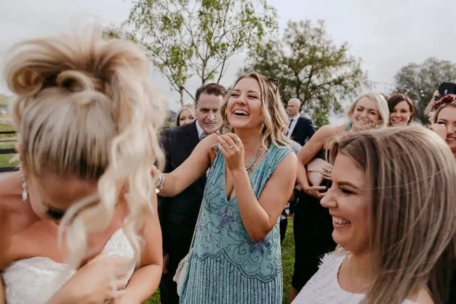 Guests laughing together around the bride outside.