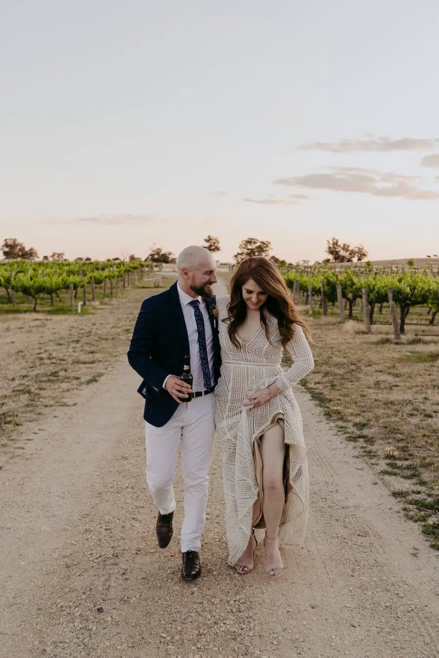 Couple walking together along a vineyard path at dusk.