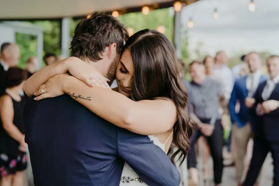 Woman embracing a man in a blue suit among gathered guests.