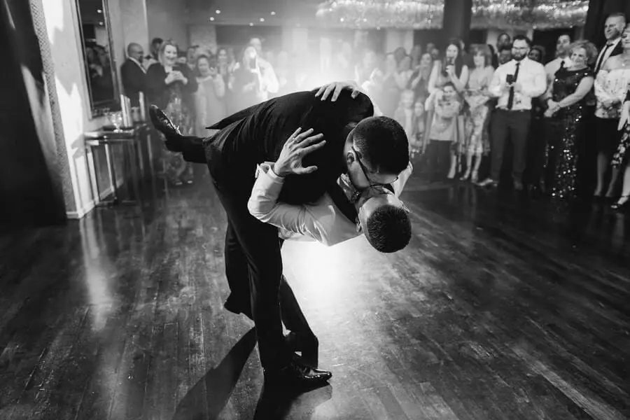 Black-and-white photograph of a groom dipping and kissing the bride on a dance floor.