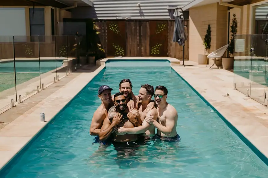 Men laughing together in a swimming pool.