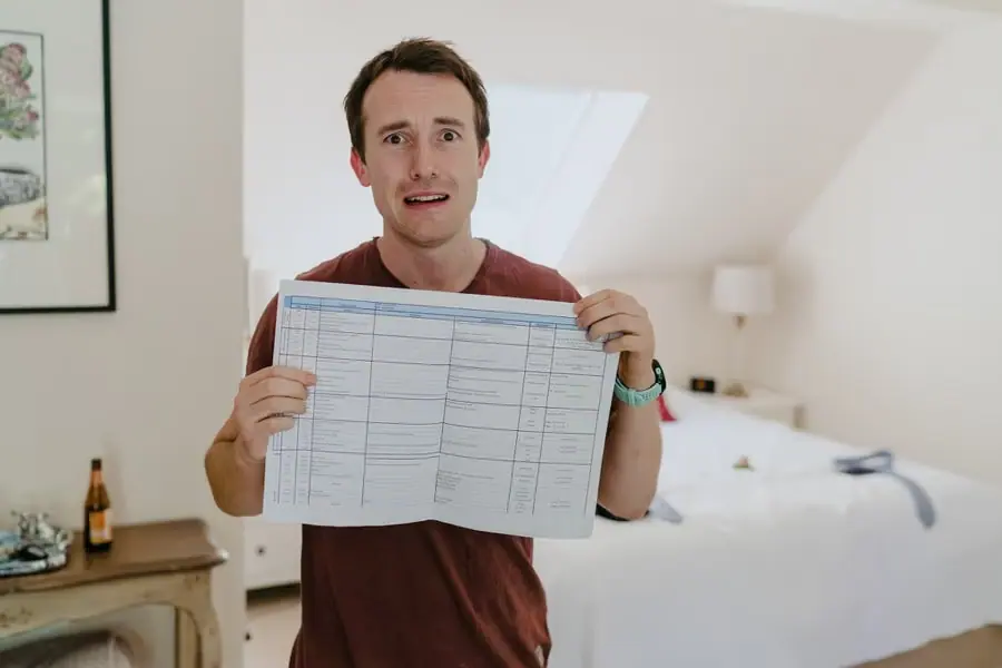 Man holding up a printed planning sheet inside a bedroom