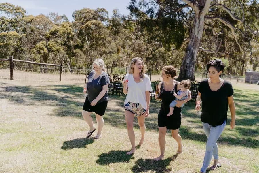 Four women walking across a lawn with one carrying a small child