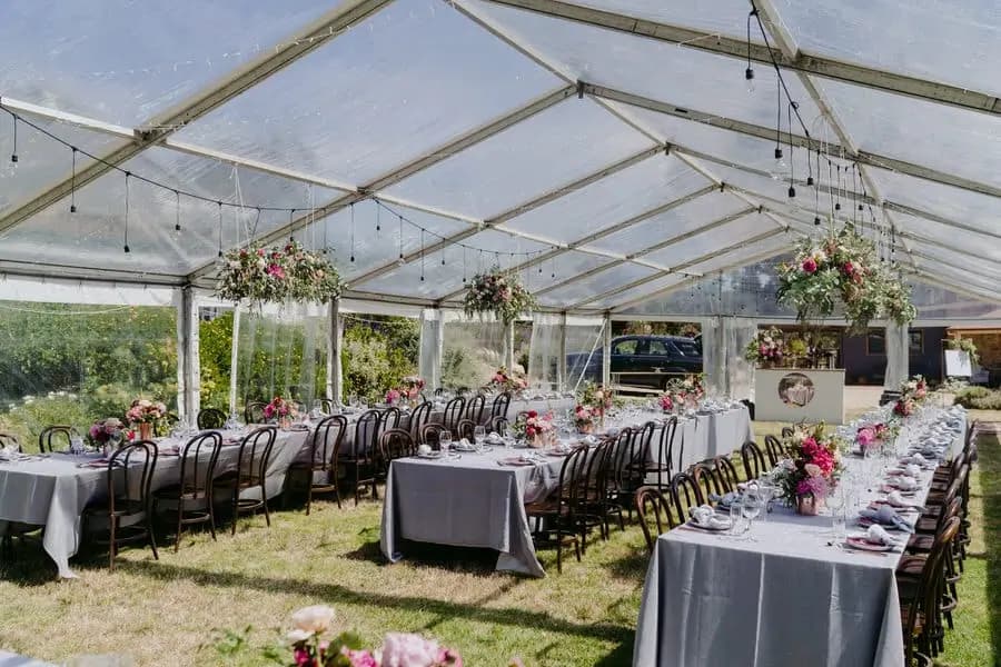 Wide view of the reception marquee with long tables and hanging flowers