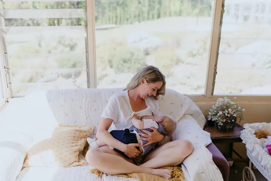 Bride sitting on a bed while holding and smiling at a baby