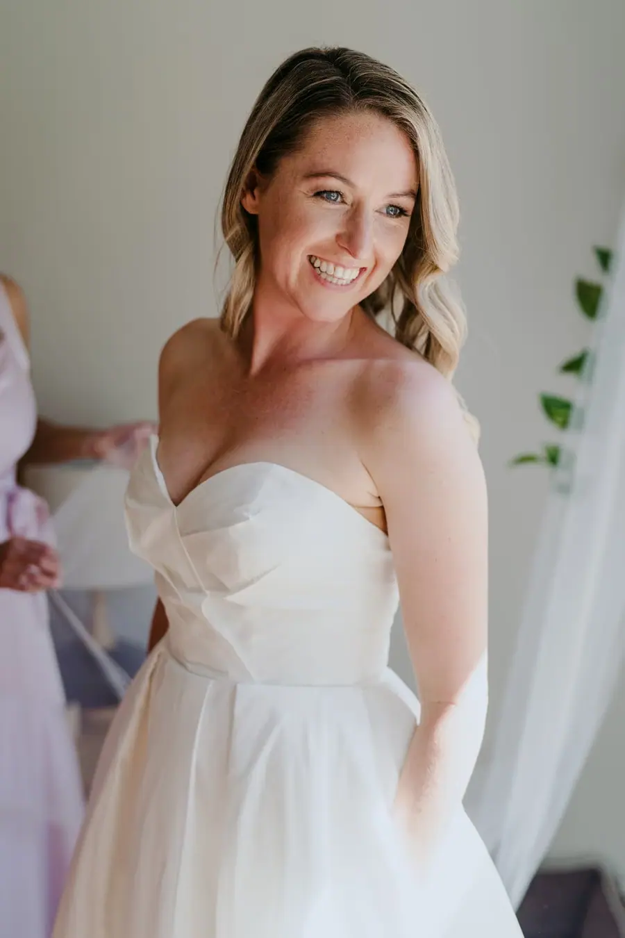 Bride smiling while looking to one side in her strapless wedding dress