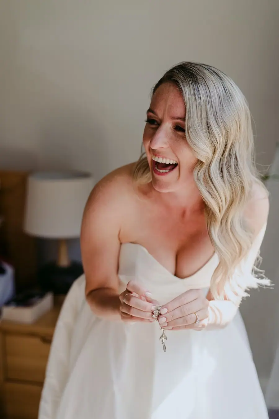 Bride laughing while looking down at her hands indoors