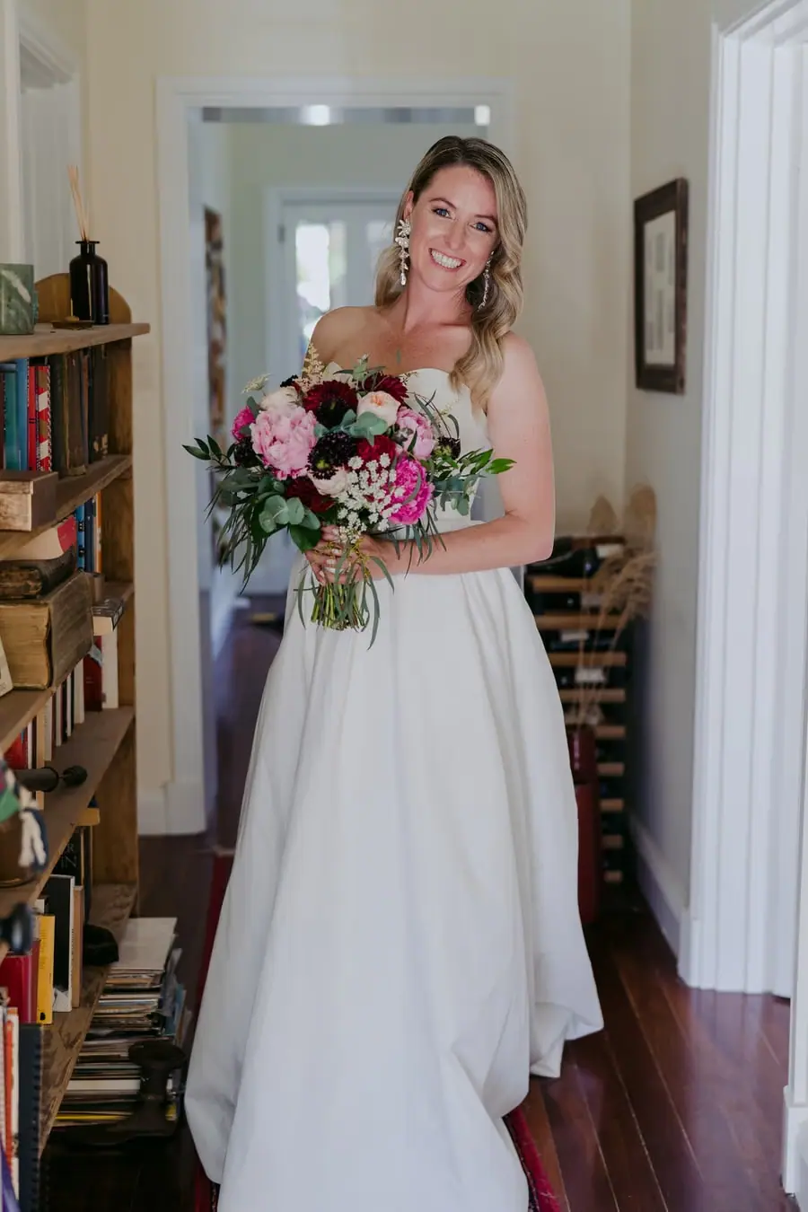 Bride smiling in a doorway while holding her wedding bouquet