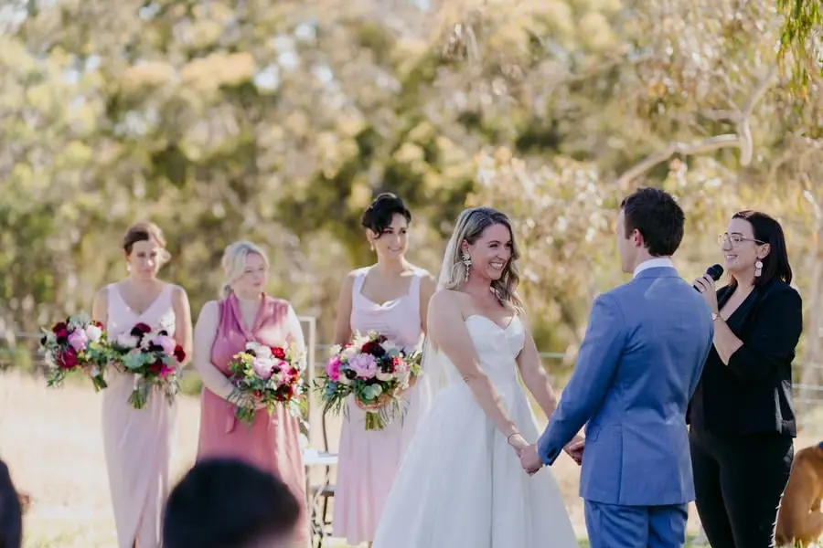 Bride and groom holding hands beside the celebrant and bridesmaids